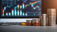Piles of coins in front of computer screen showing analytical data